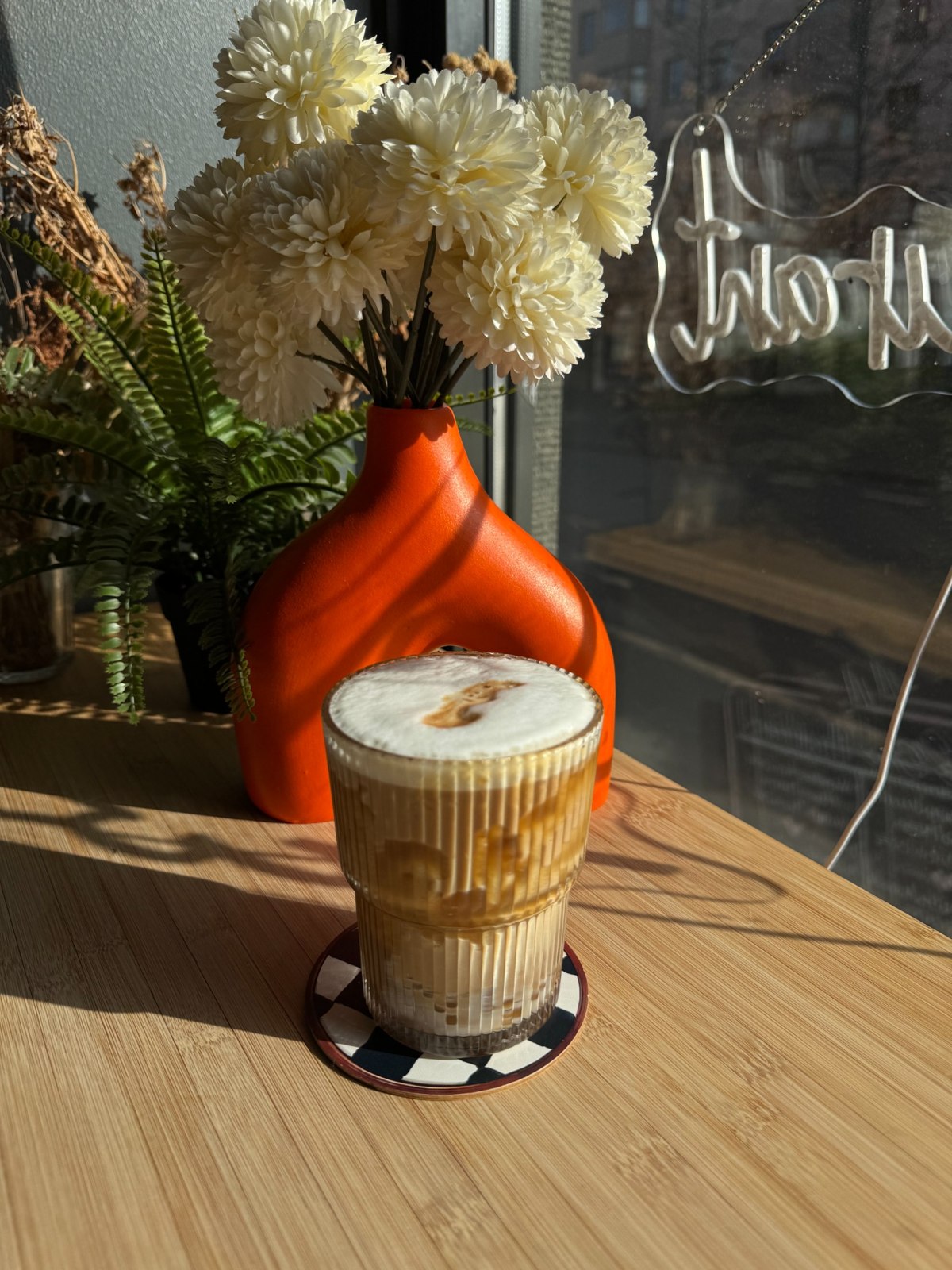 A creamy iced drink in a ribbed glass on a sunny table