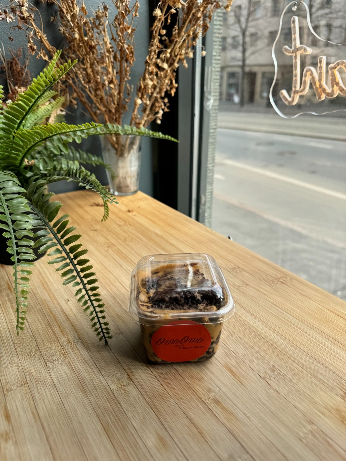 A layered dessert in a takeaway container on the café counter